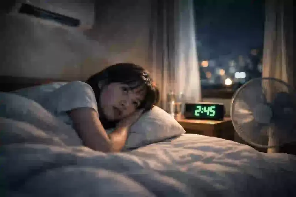 夏の夜、暑さと湿度で眠れず、エアコンをつけるか迷っている様子を表した図